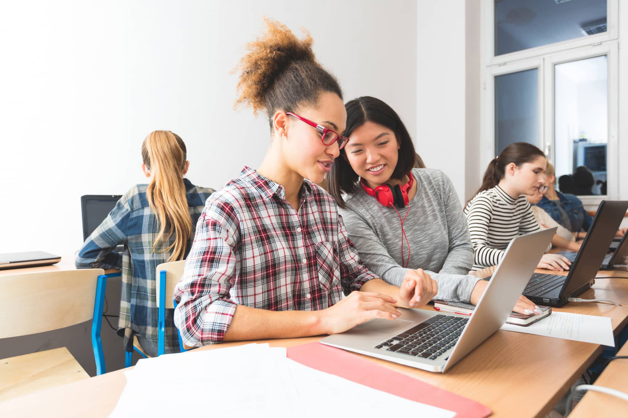 Two high school students working on extension activities on laptops